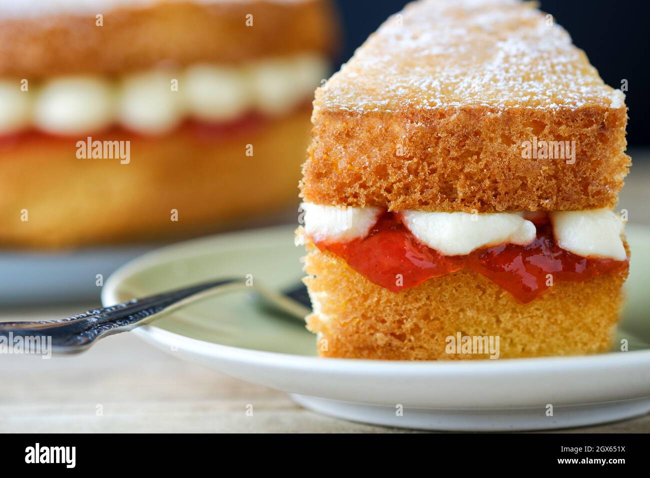 Die Torte ist eine Portion oder ein Stück eines frisch hausgemachten Victoria Sponge- und Sandwichkuchens und hat eine Füllung aus Erdbeermarmelade und Buttercreme Stockfoto