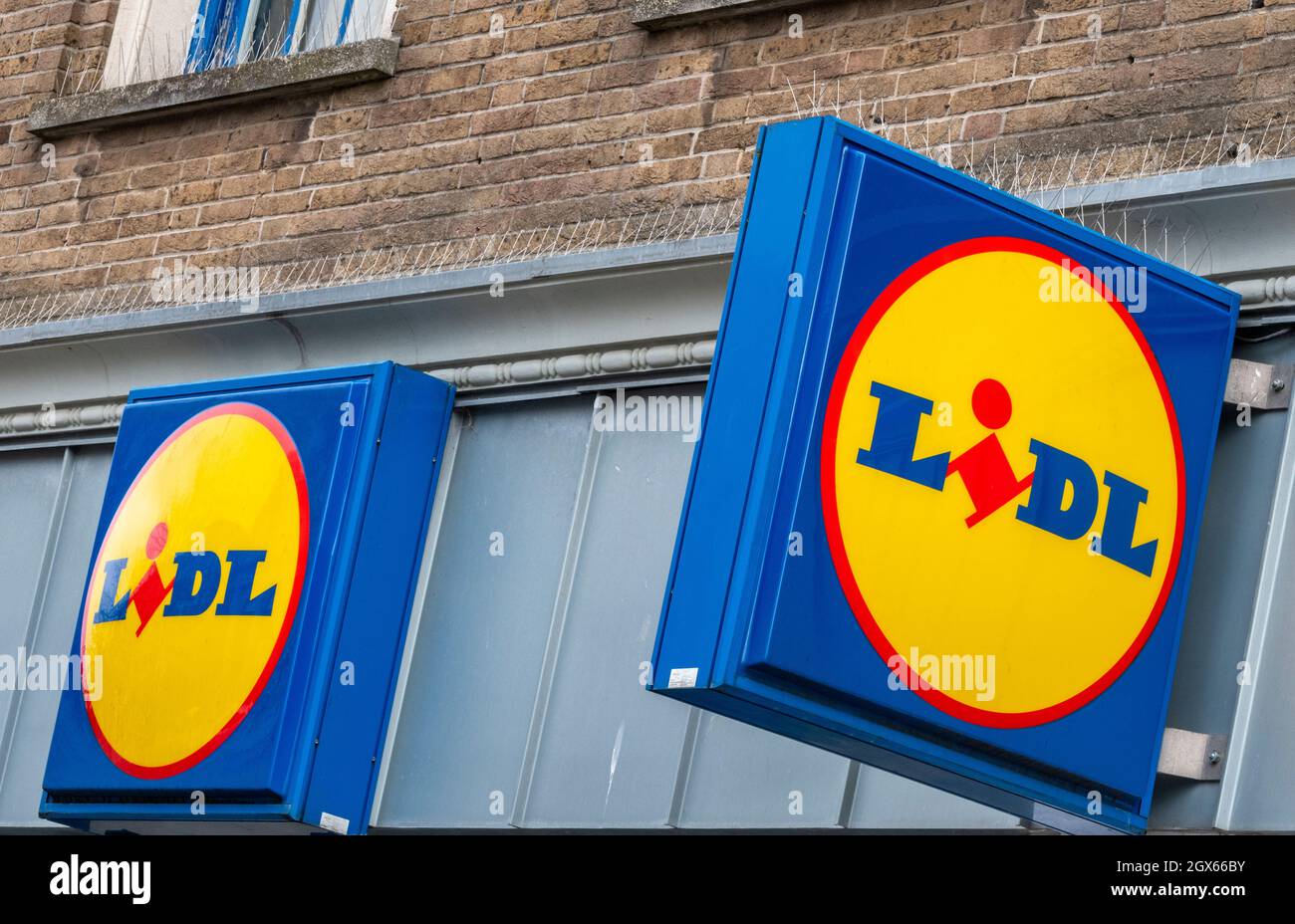 lidl-Supermarkt-Schilder in blau-gelber Farbgebung auf dem Display vor einem großen Supermarkt der großen Lebensmittelkette. Stockfoto