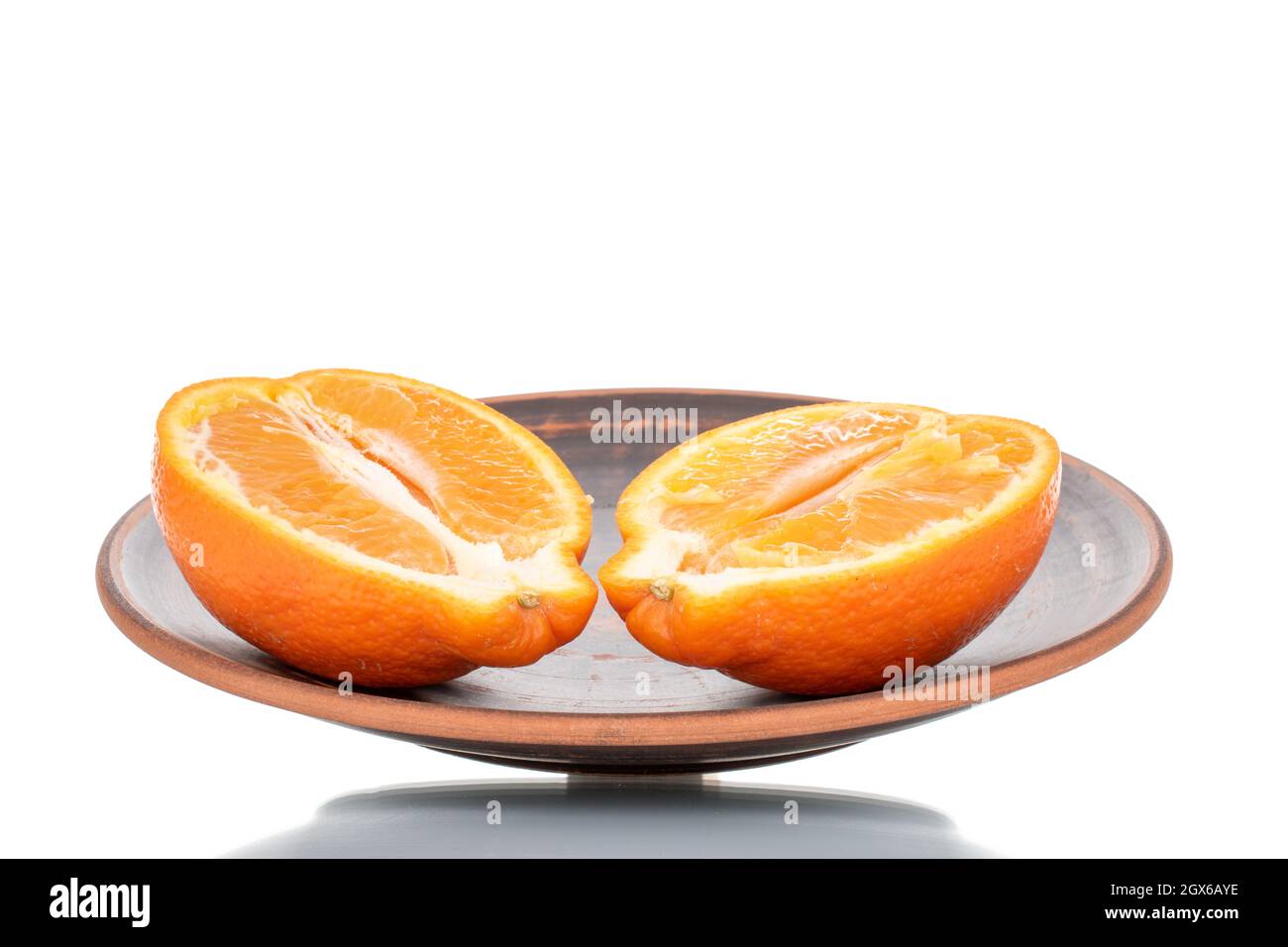 Zwei Hälften organisch reifer minneola auf einer Keramikschale, Nahaufnahme, isoliert auf Weiß. Stockfoto