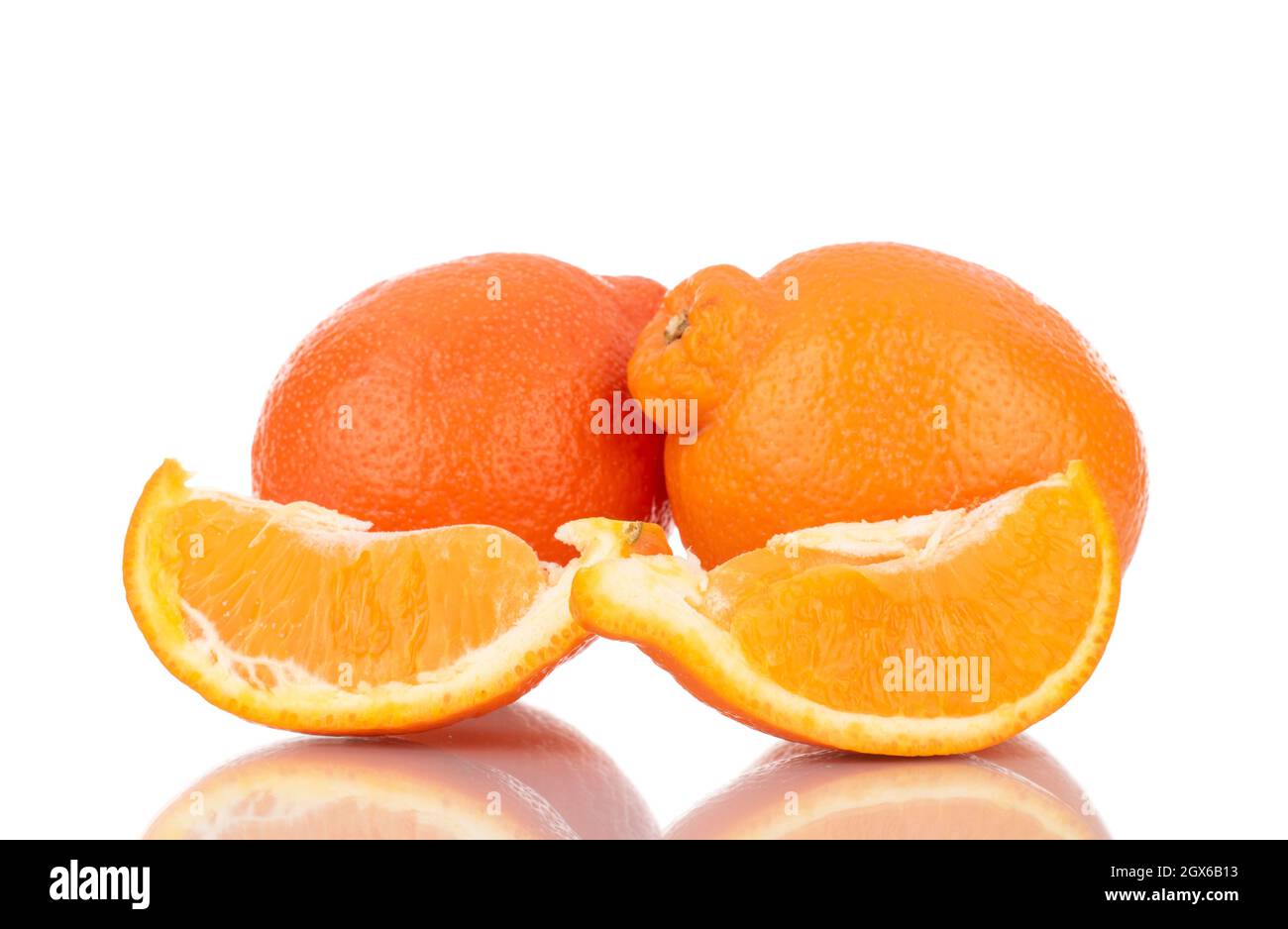 Zwei Scheiben und zwei ganze süße Bio-minneola, Nahaufnahme isoliert auf Weiß. Stockfoto