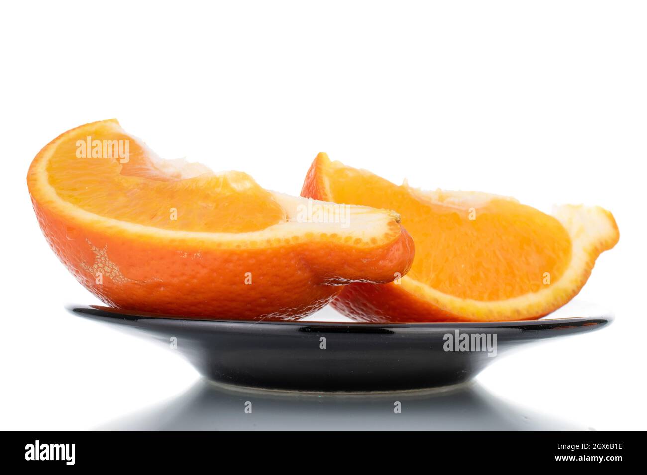 Zwei Scheiben organisch reifer minneola auf einer Keramikschale, Nahaufnahme, isoliert auf Weiß. Stockfoto