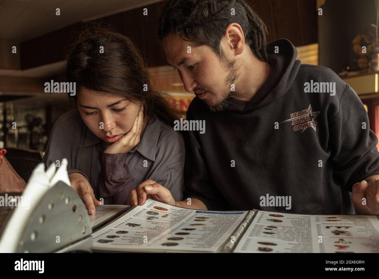 Junge Frau und Mann schauen sich ein Menü in einem Restaurant an, Old Goa, Indien Stockfoto