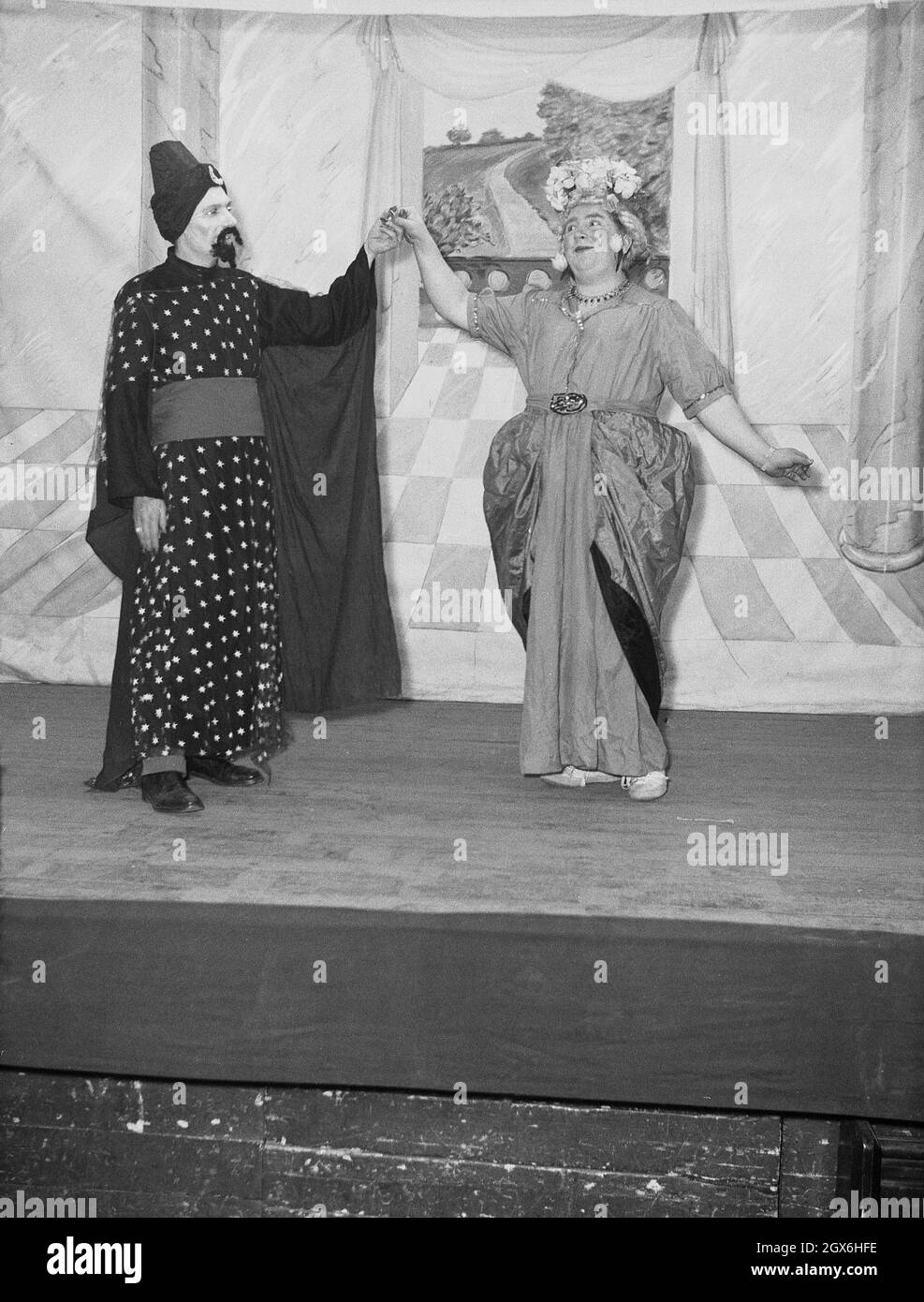 1957, historisch, zwei männliche Schauspieler auf der Bühne im Stück Aladdin, basierend auf einer nahöstlichen Volksgeschichte oder Fabel über den Sohn einer armen Witwe in china, der Besitzer einer magischen Lampe wird, England, Großbritannien. Ein Schauspieler spielt den Genie, während der andere Widow Twankey ist, eine weibliche Figur, die von einem Mann gespielt wird. Die Geschichte von Aladdin wurde 1788 erstmals in Covent Garden, London, aufgeführt. Stockfoto