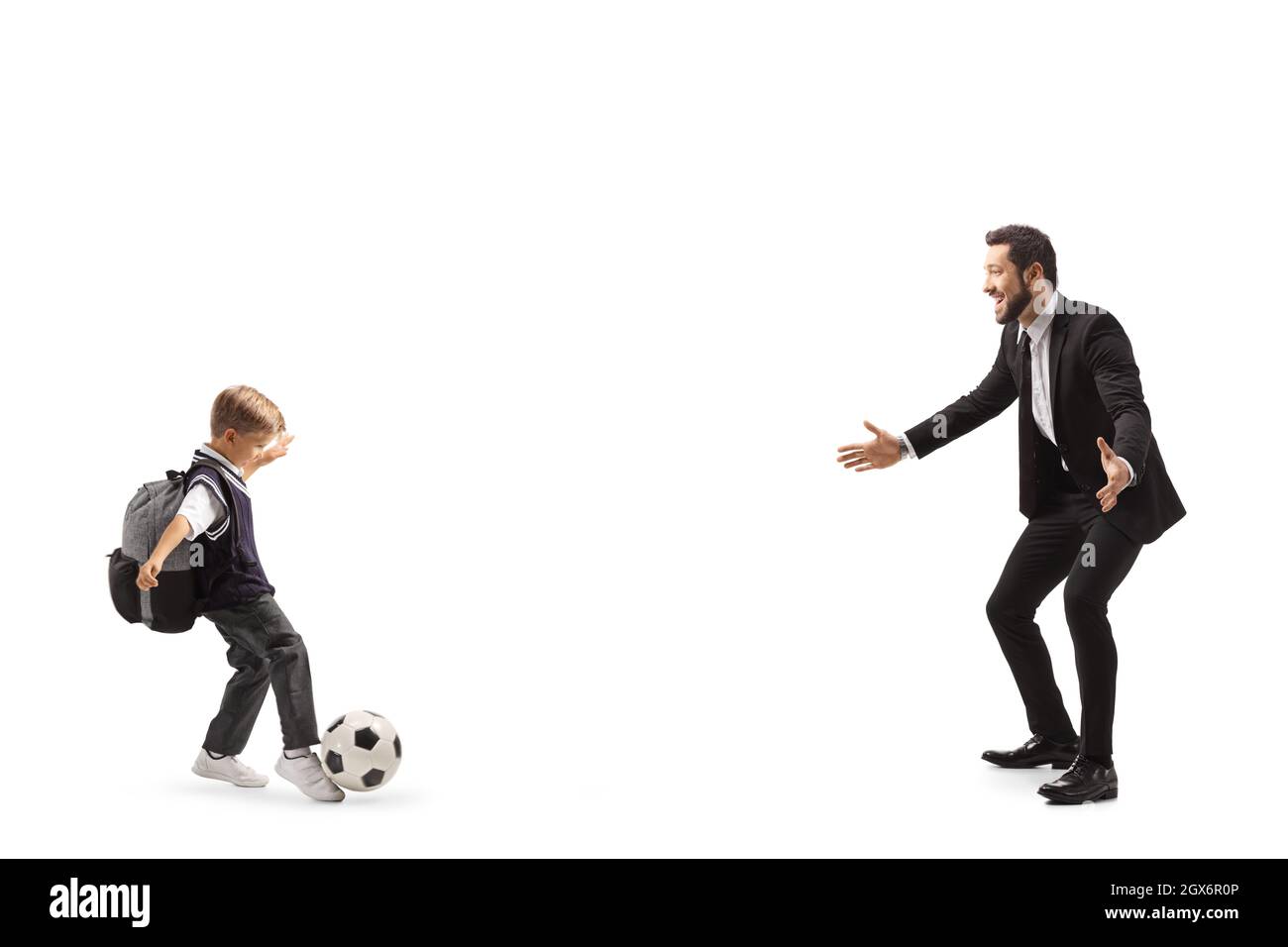 In voller Länge Profilaufnahme eines Schuljungen, der Fußball spielt, während sein Vater auf weißem Hintergrund isoliert ist Stockfoto