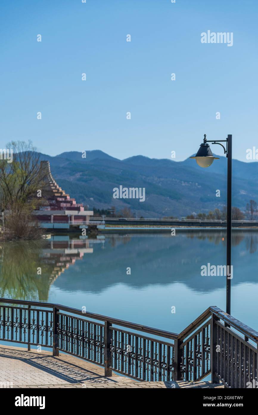 Ein pyramidenähnliches Gebäude an der Küste eines Sees in Bulgarien. Berühmte Attraktion. Berge in der Ferne. Sonniger Tag. Stockfoto
