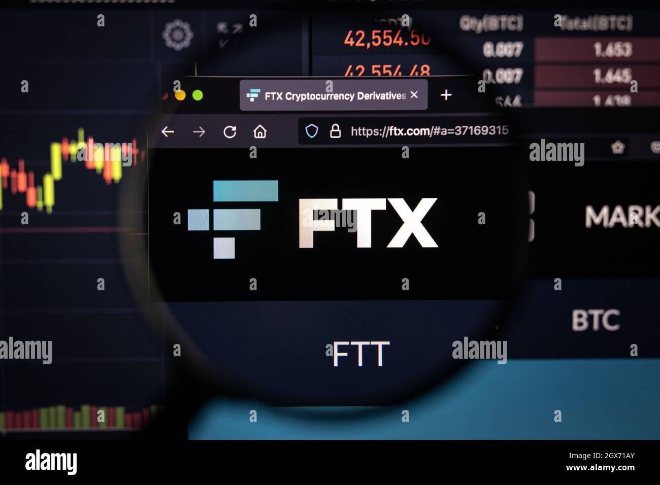 FTX-Firmenlogo auf einer Website mit verschwommenen Börsenentwicklungen im Hintergrund, die auf einem Computerbildschirm durch eine Lupe gesehen werden Stockfoto