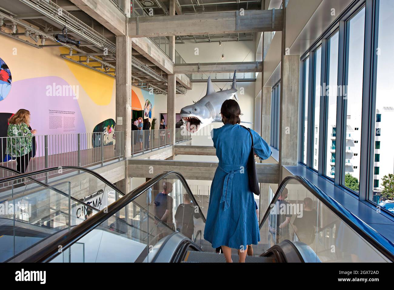 Frau auf der Rolltreppe unter einem Shark-Modell aus dem Film Jaws, das im Academy Museum of Motion Picturs in Los Angeles, Kalifornien, gezeigt wird Stockfoto