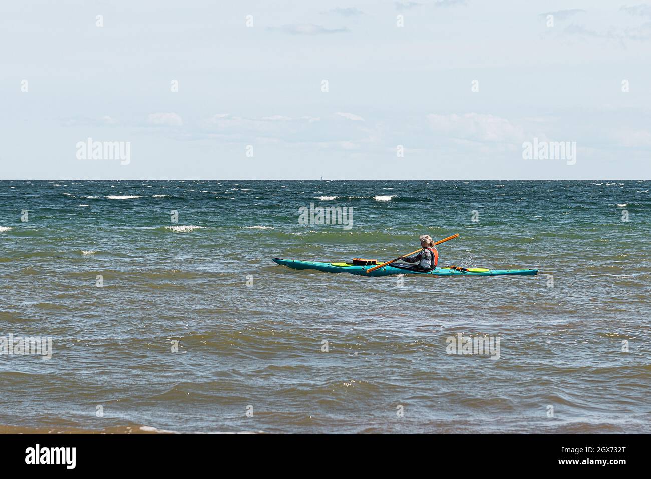 Mädchen mit Schwimmweste paddelt allein in einem Kajak auf dem offenen Meer, Vejle, Dänemark, 31. August 2021 Stockfoto
