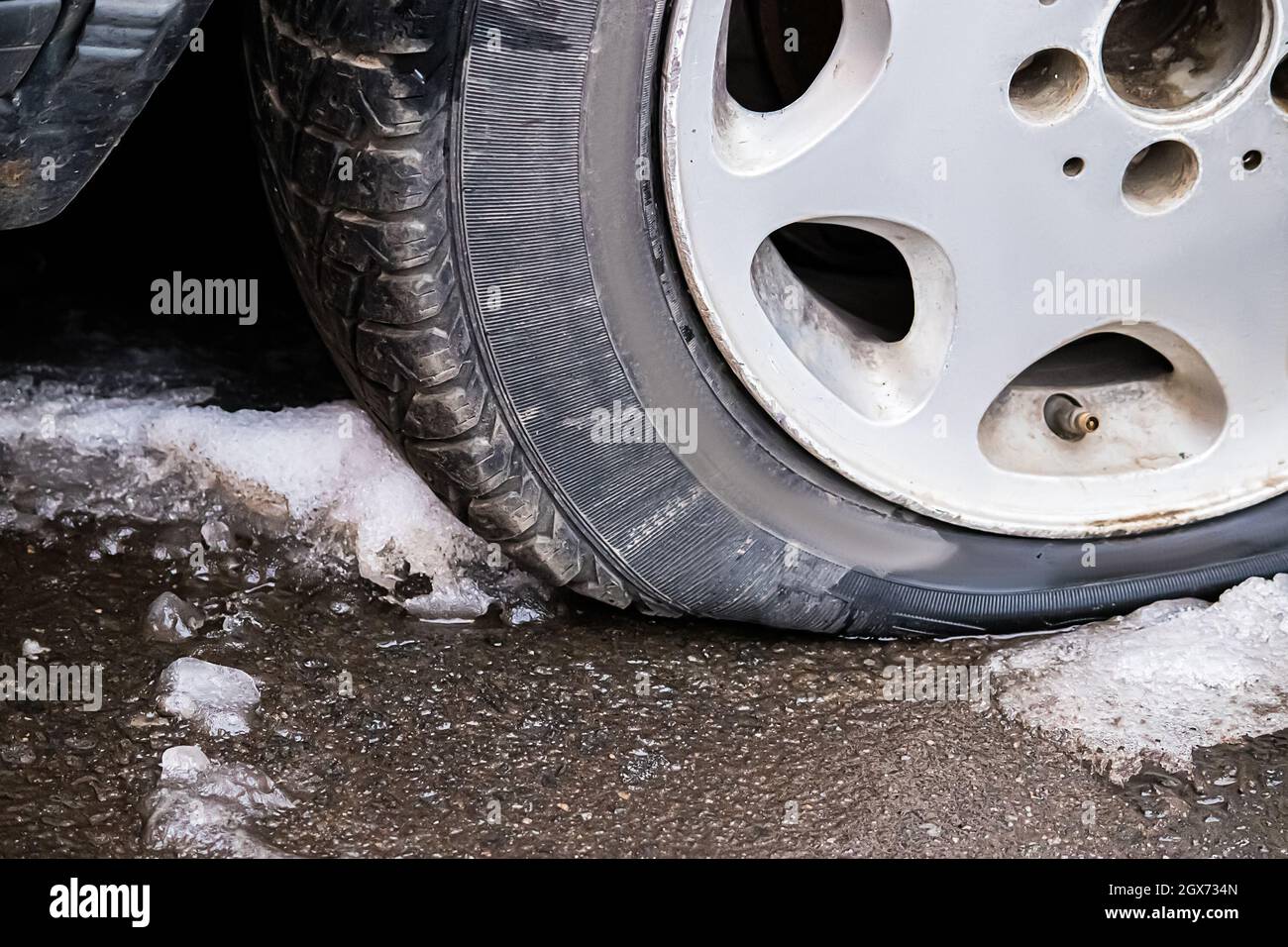 Nahaufnahme des Platten Reifens. Unfall auf der Straße im Winter. Durchbrochenes Rad des Autos. Stockfoto