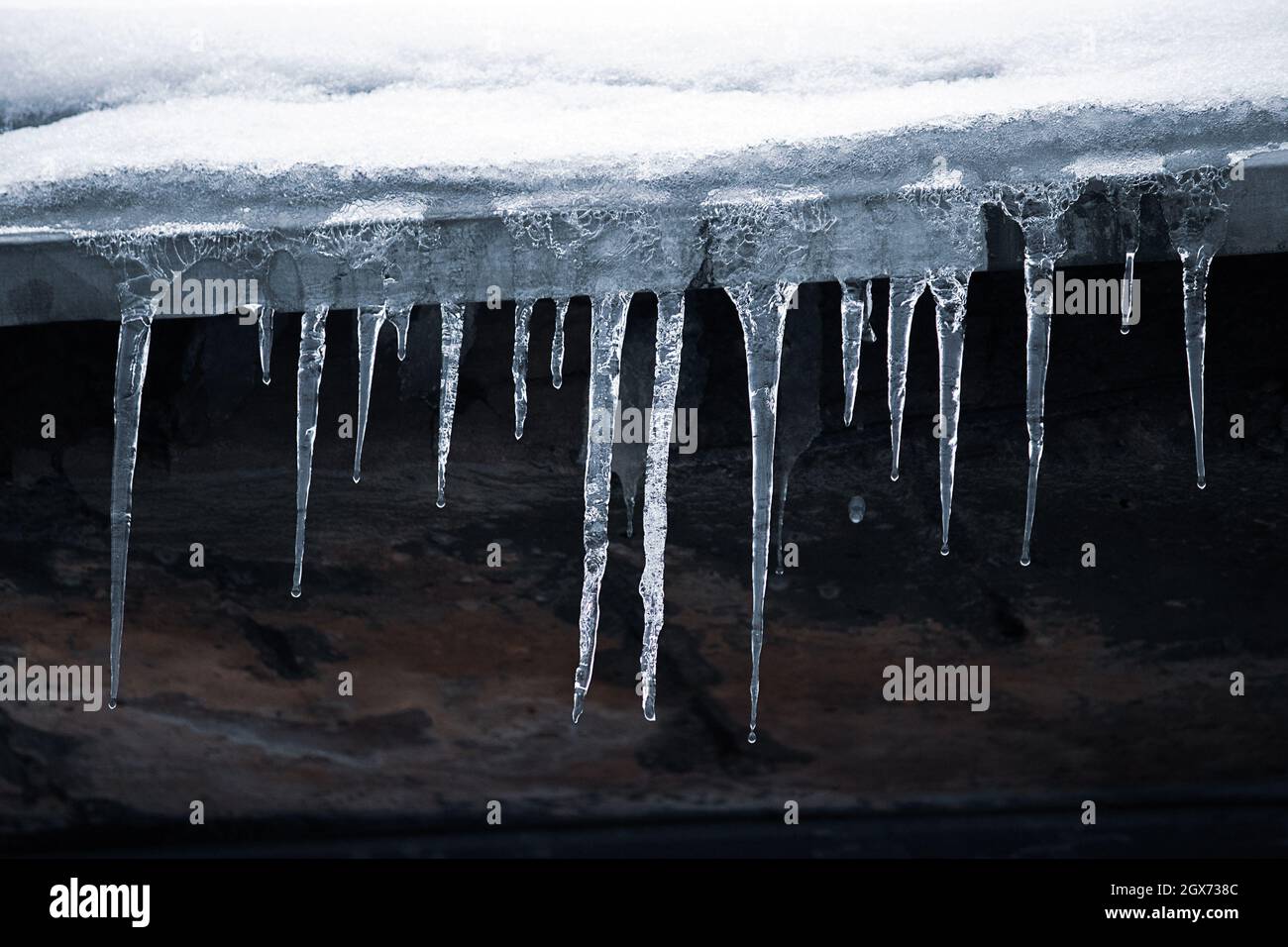 Eiszapfen auf dem Dach. Gefährliche Vereisung. Eisstalaktiten auf dem Haus. Schlechte Instandhaltung von Wohngebäuden im Winter. Stockfoto