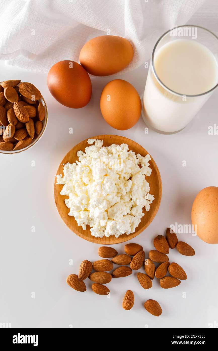 Eine Reihe von gesunden Protein-Lebensmittel für eine ausgewogene Ernährung. Hüttenkäse, Eier und Nüsse auf weißem Hintergrund. Stockfoto