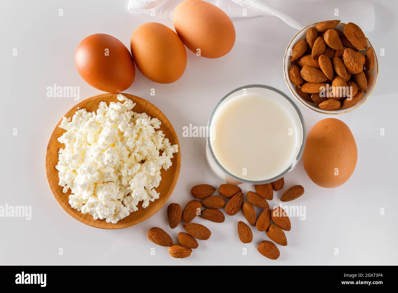 Eine Reihe von gesunden Protein-Lebensmittel für eine ausgewogene Ernährung. Hüttenkäse, Eier und Nüsse auf weißem Hintergrund. Stockfoto