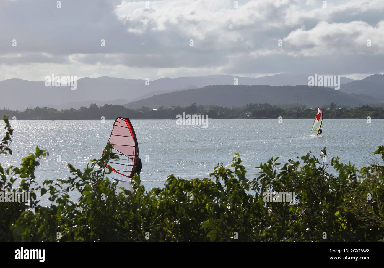 Junge und ältere Menschen üben Kitesurfen und Windsurfen in der Lagune von Ibiraquera. Stockfoto