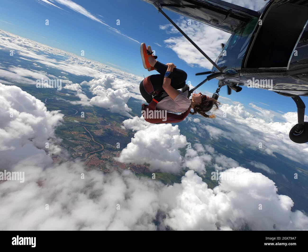 Junge Frau Fallschirmspringer lächelt im freien Fall. Perfektes Konzept von Glück und Freiheit. Stockfoto