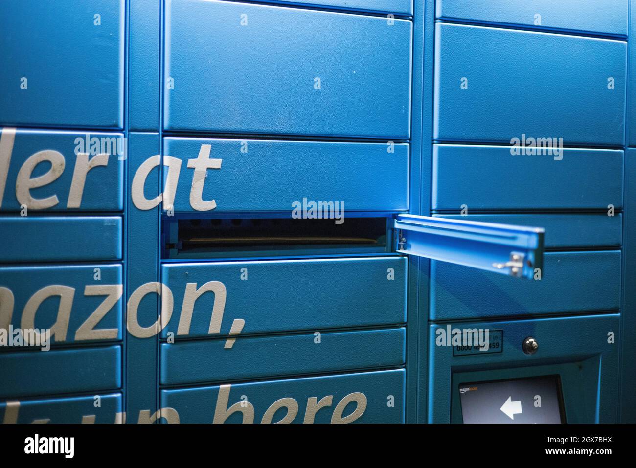 Amazon Hub locker gesehen in der Nacht auf dem Parkplatz des Kenley Bahnhof, South London. Stockfoto