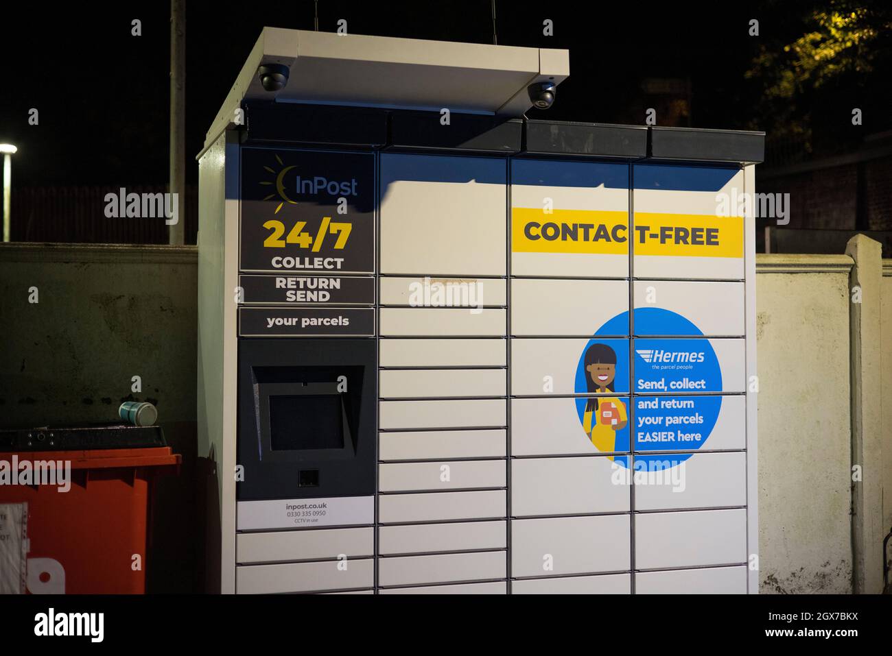 InPost Paketabholung Schließfach gesehen in der Nacht auf dem Parkplatz des Kenley Bahnhof, South London. Stockfoto