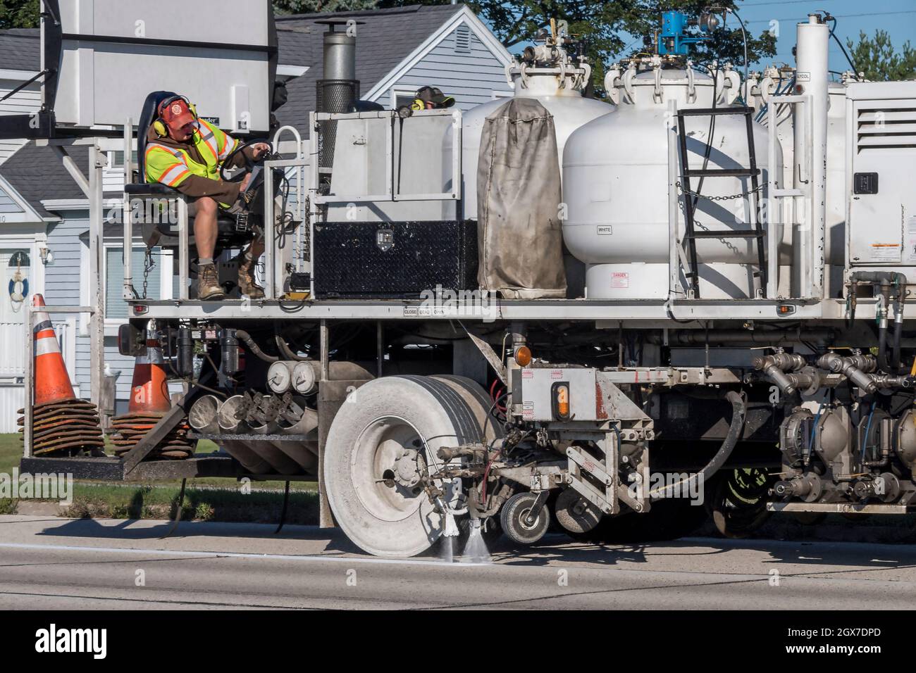 Highway-Wartungsarbeiter auf Lack striper Fahrzeug Steuerung Spritzlackierung weiße Mittellinie auf Straßenbelag. Stockfoto