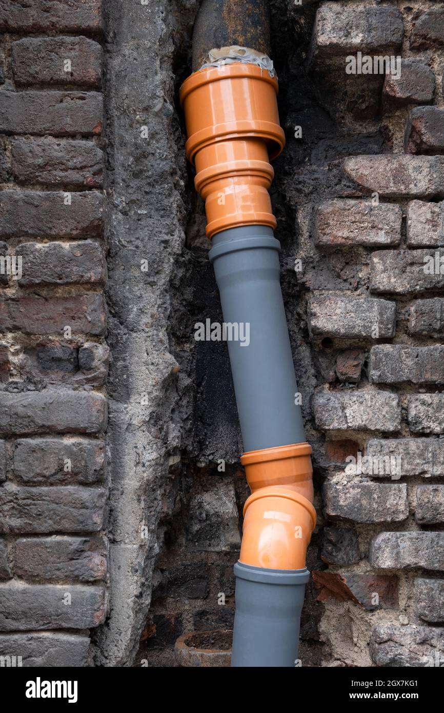 Vorgefertigte feste Entwässerung aus Kunststoffrohren von Klempner in der Wand des alten Gebäudes in Europa hergestellt. Konstruktionsingenieurkonzept Stockfoto