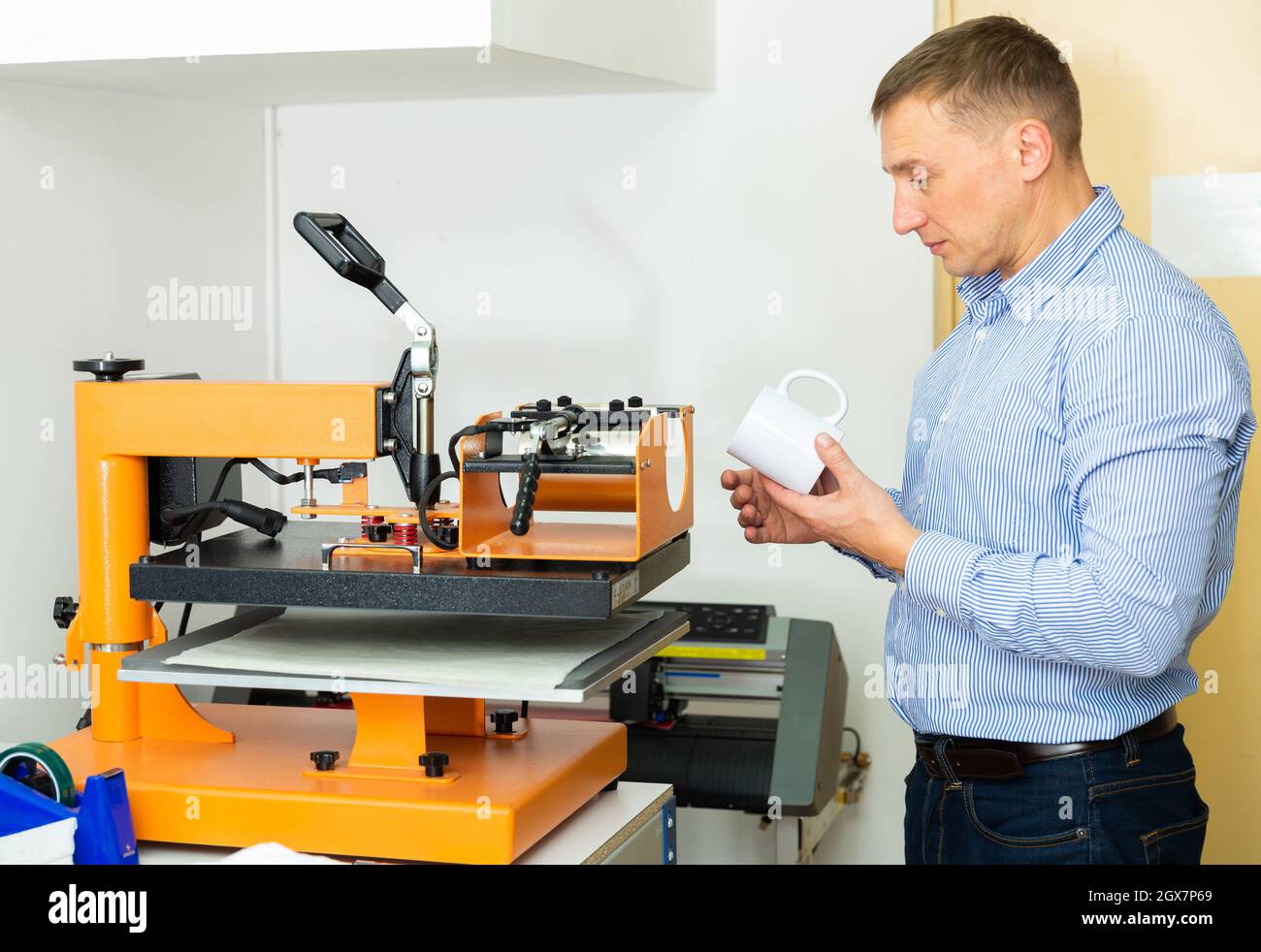 Man Druck auf Kaffeetassen in Werkstatt Stockfoto