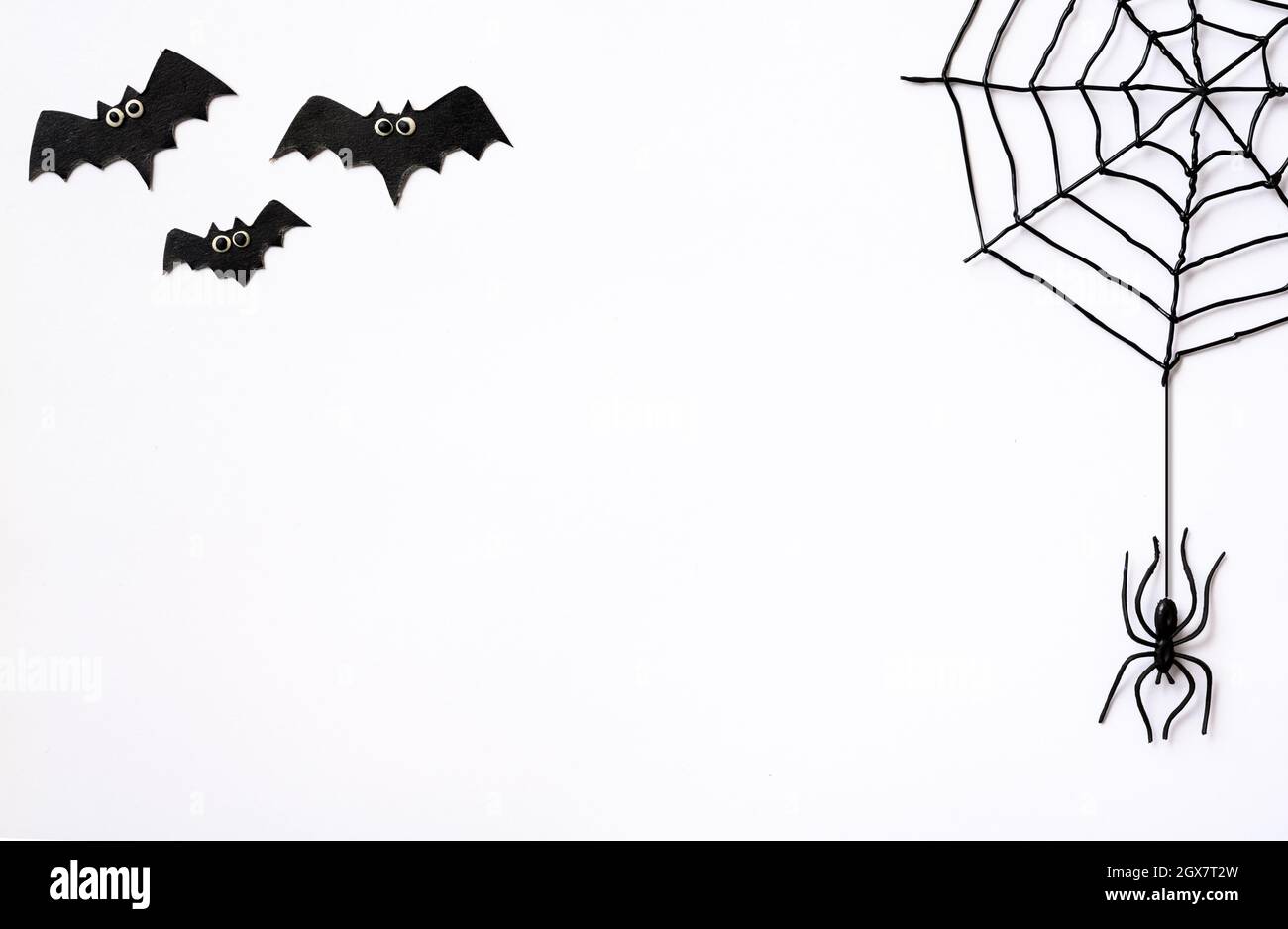 Halloween-Thema mit schwarzen Spinnen, Netz und Fledermäuse. Gruselige Halloween-Objekte auf weißem Hintergrund mit Platz für Text, flach liegend. Minimalistisches Hallowen gree Stockfoto