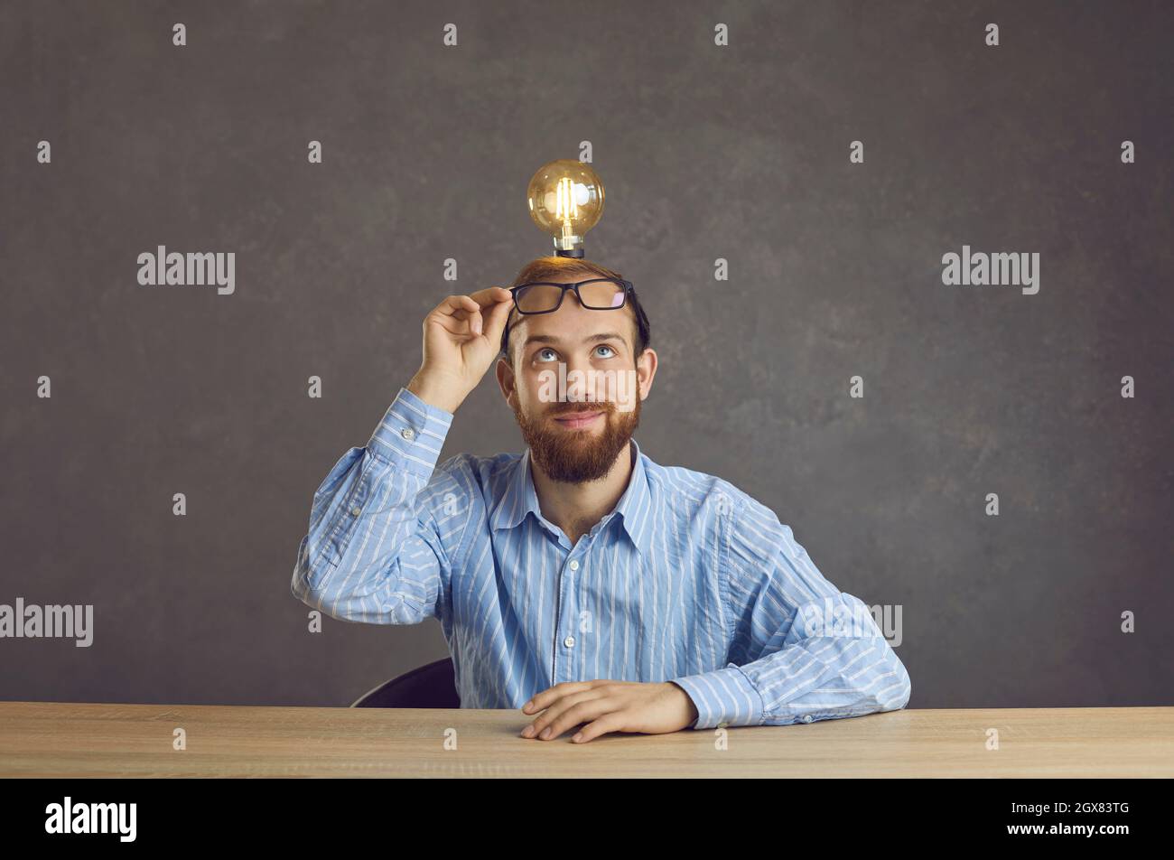 Mann Freiberufler mit Glühbirne über Kopf sitzen am Tisch teilen helle Idee Stockfoto