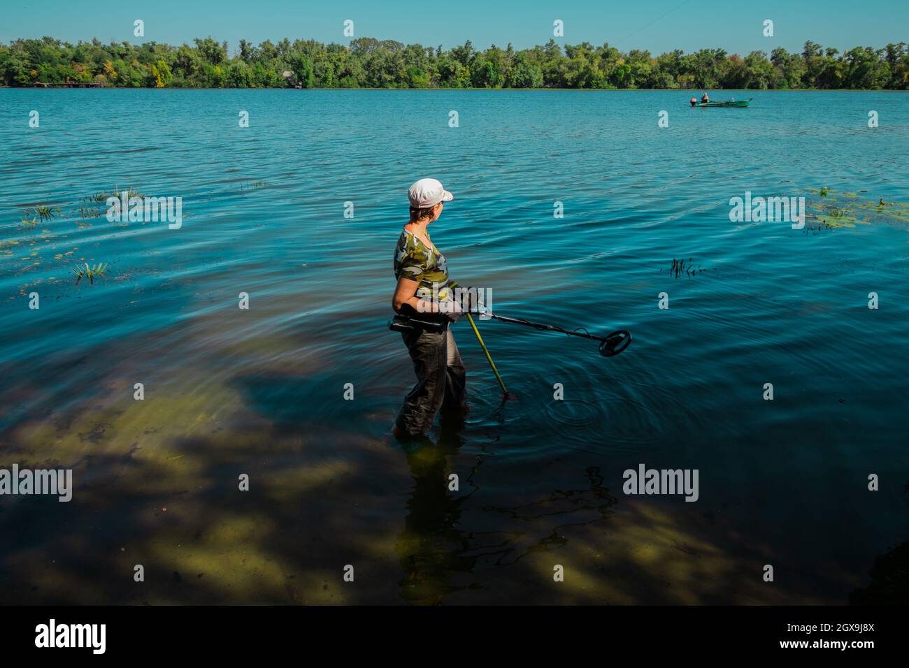 Eine Frau sucht mit einem Metalldetektor nach Schätzen im Wasser. Stockfoto