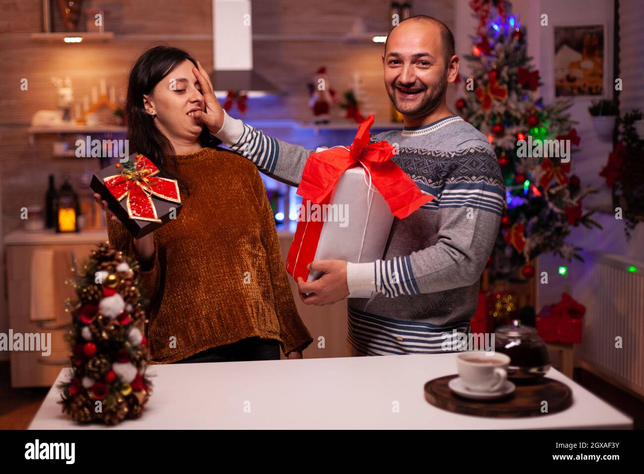 Glückliche Familie genießen Zeit zusammen während der weihnachtsfeiertage halten Weihnachten dekoriert Geschenk mit Band darauf. Aufgeregt verheiratetes Paar feiert Winterfestzeit Stockfoto