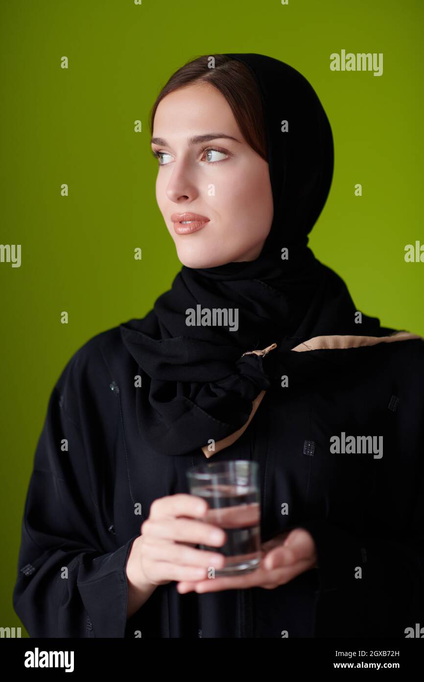 Moderne muslimische Frau in Abaya hält eine Dattefrucht und ein Glas Wasser von ihr. Konzept Feier des iftar im ramadan und Ende des Festes Stockfoto