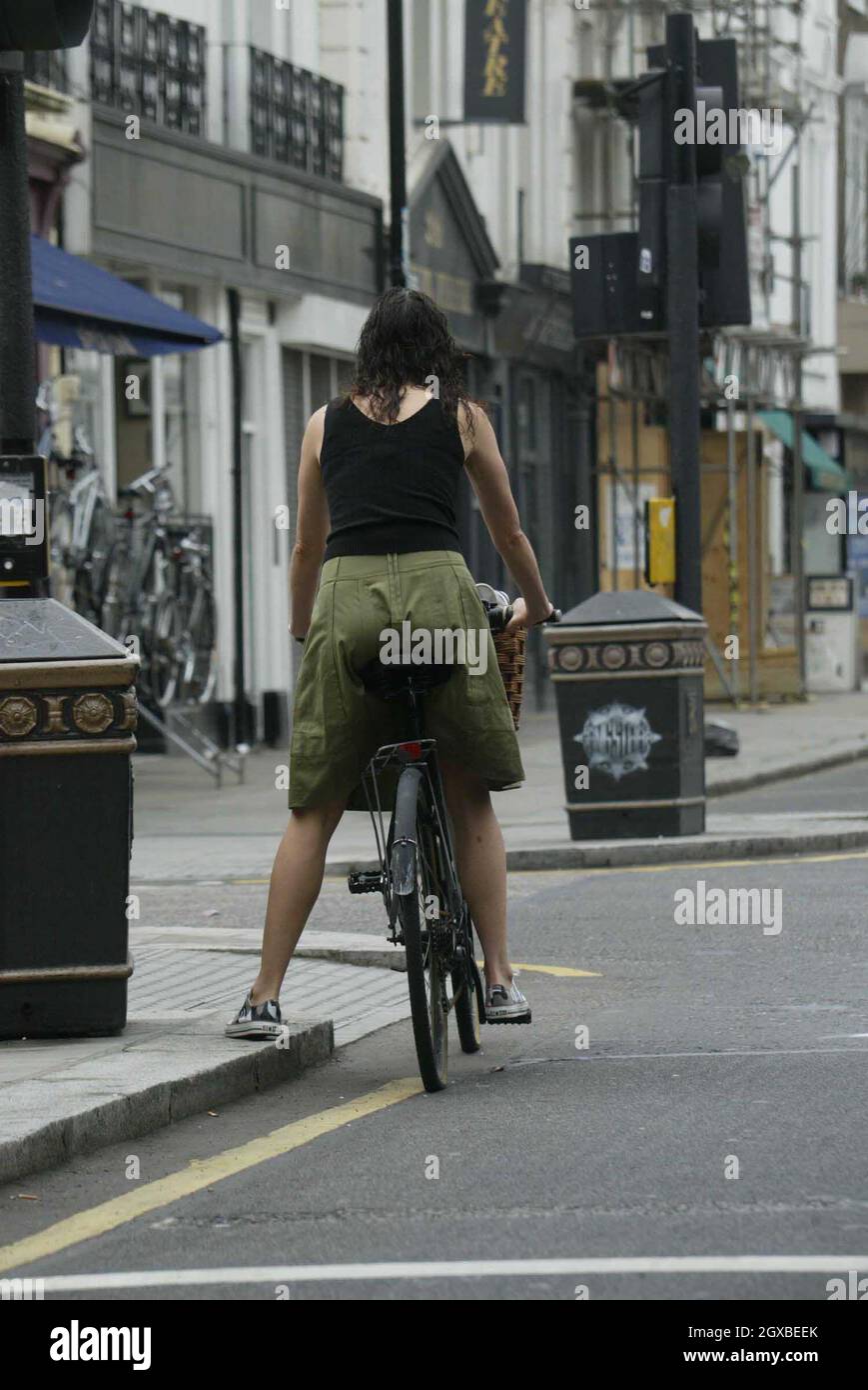 Minnie Driver versucht, ihre Einkaufstüten auszugleichen, während sie auf ihrem Fahrrad durch den Verkehr von West London sruggelt. Stockfoto