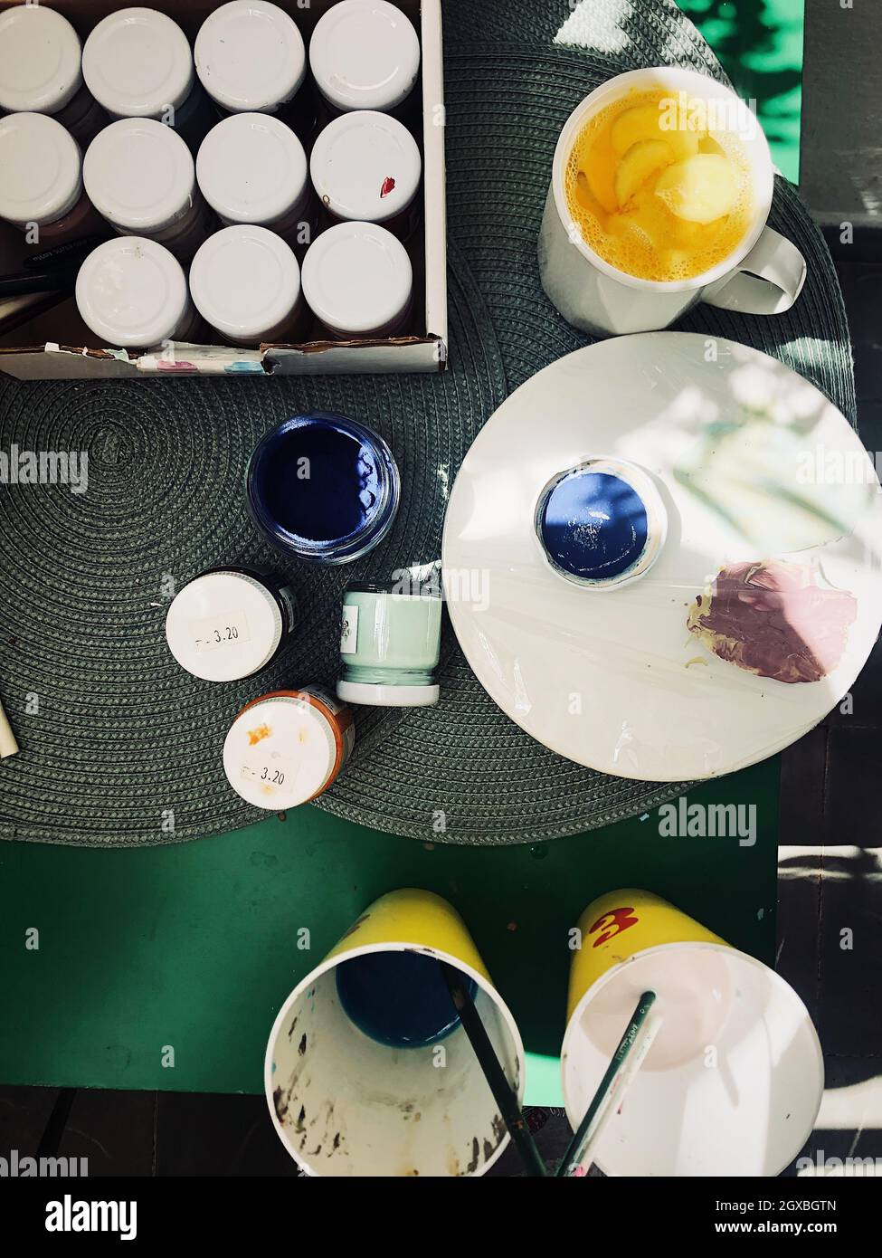 Tasse Ingwer und Kurkuma-Tee auf einem Tisch mit Farbtöpfen und Malgeräten Stockfoto