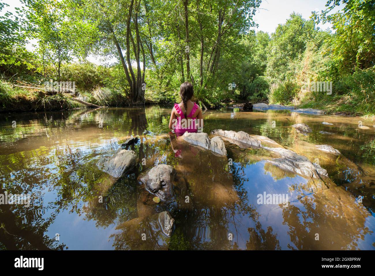 Kleines Mädchen, das den Fluss Gevora, La Codosera, Badajoz, Extremadura, Spanien entdeckt. Idyllische Lage mit kristallklarem Wasser und Wäldern am Flussufer. Stockfoto