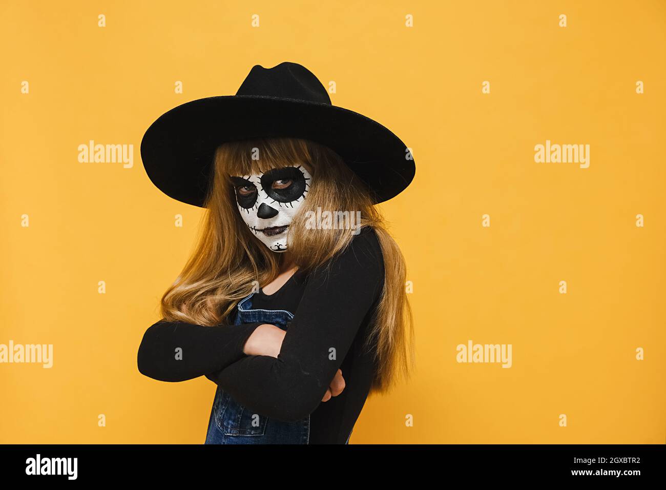 Porträt von wütend traurig kleinen blonden Mädchen Kind mit Halloween Make-up-Maske, trägt schwarzen Hut, gekreuzte Arme, unglücklich zur Seite schauen Stockfoto