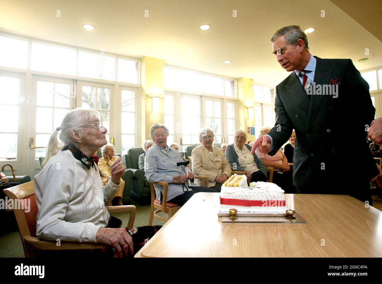 Prinz Charles, Prinz von Wales, chattet mit der 105-jährigen Hettie Hyndman, während sie am Freitag, dem 23. März 2007, mit einem Geburtstagskuchen in Whiteley Village in Walton-on-Thames, Surrey, sitzt. Der Prinz besuchte die Altersgruppe aufgrund seiner Rolle als Schirmherr des Almshouse-Vereins. Stockfoto