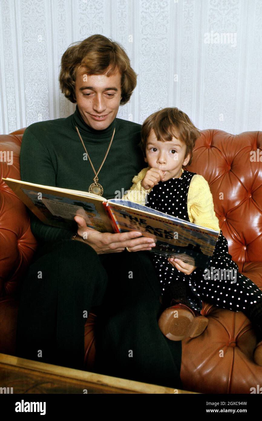 Bee Gees Singer Robin Gibb liest seinem Sohn Spencer, um 1974 Stockfoto