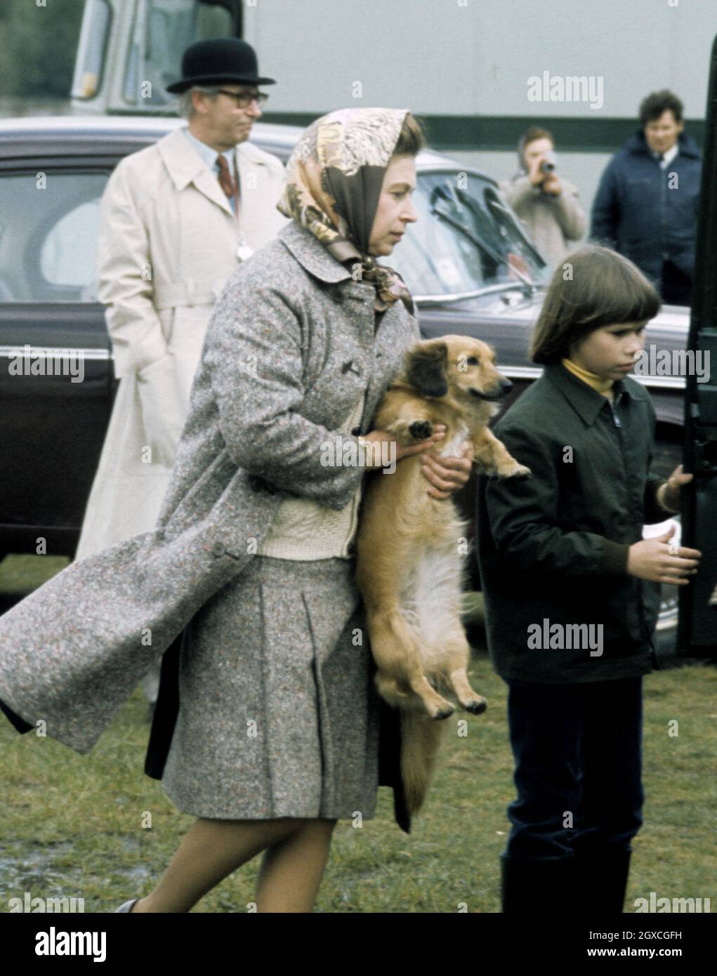 Königin Elizabeth II, begleitet von Lady Sarah Armstrong-Jones, trägt am 01. Mai 1977 einen ihrer Hunde im Windsor Great Park. Stockfoto