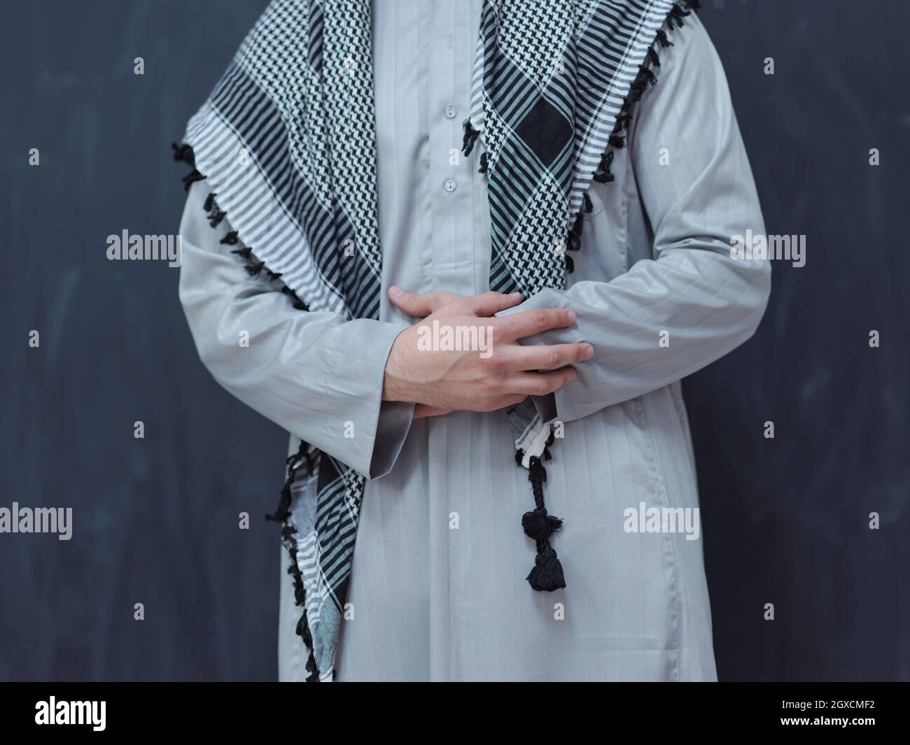 Porträt des jungen arabischen Mannes in traditioneller Kleidung vor schwarzer Tafel, die moderne islam-Mode und ramadan-Kareem-Konzept darstellt Stockfoto