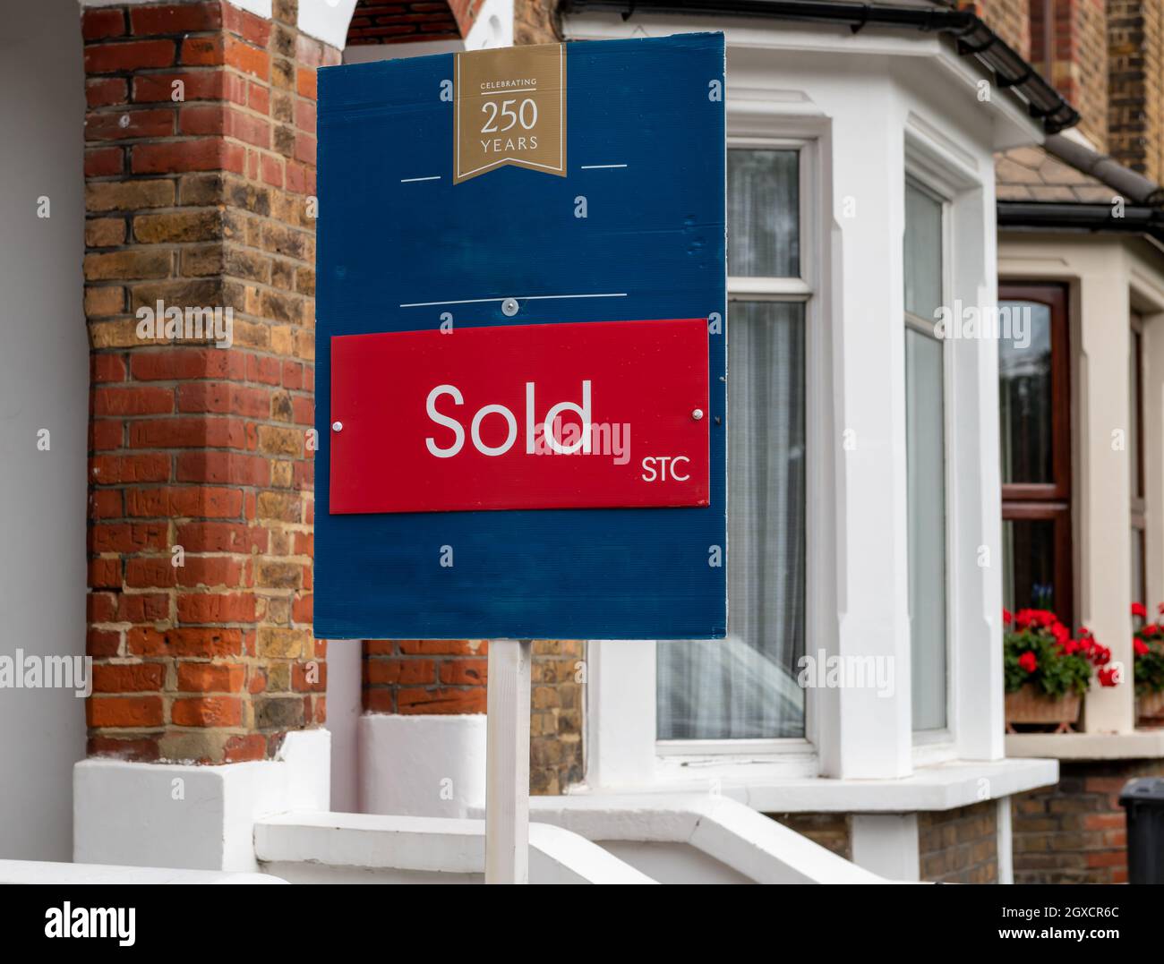 London. VEREINIGTES KÖNIGREICH. 10.03.2021. Ein Grundstück verkauft Schild vor einem Vorort Terrasse Haus mit Grundstückspreise dramatisch in der Landschaft steigen. Stockfoto