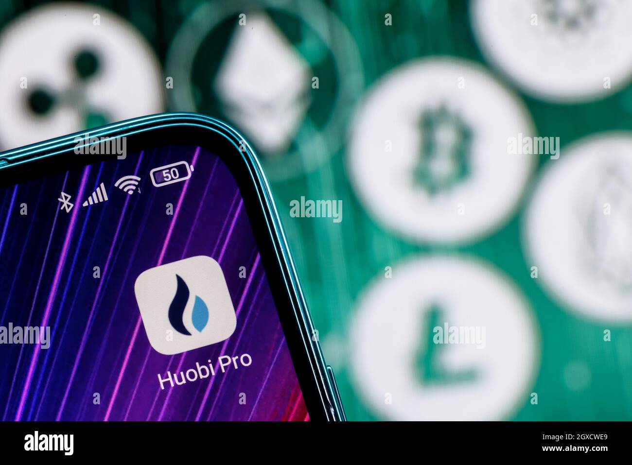 Huobi ist eine Kryptowährungsbörse. Huobi App auf dem Smartphone-Bildschirm vor dem Hintergrund der wichtigsten Kryptowährungen. Stockfoto