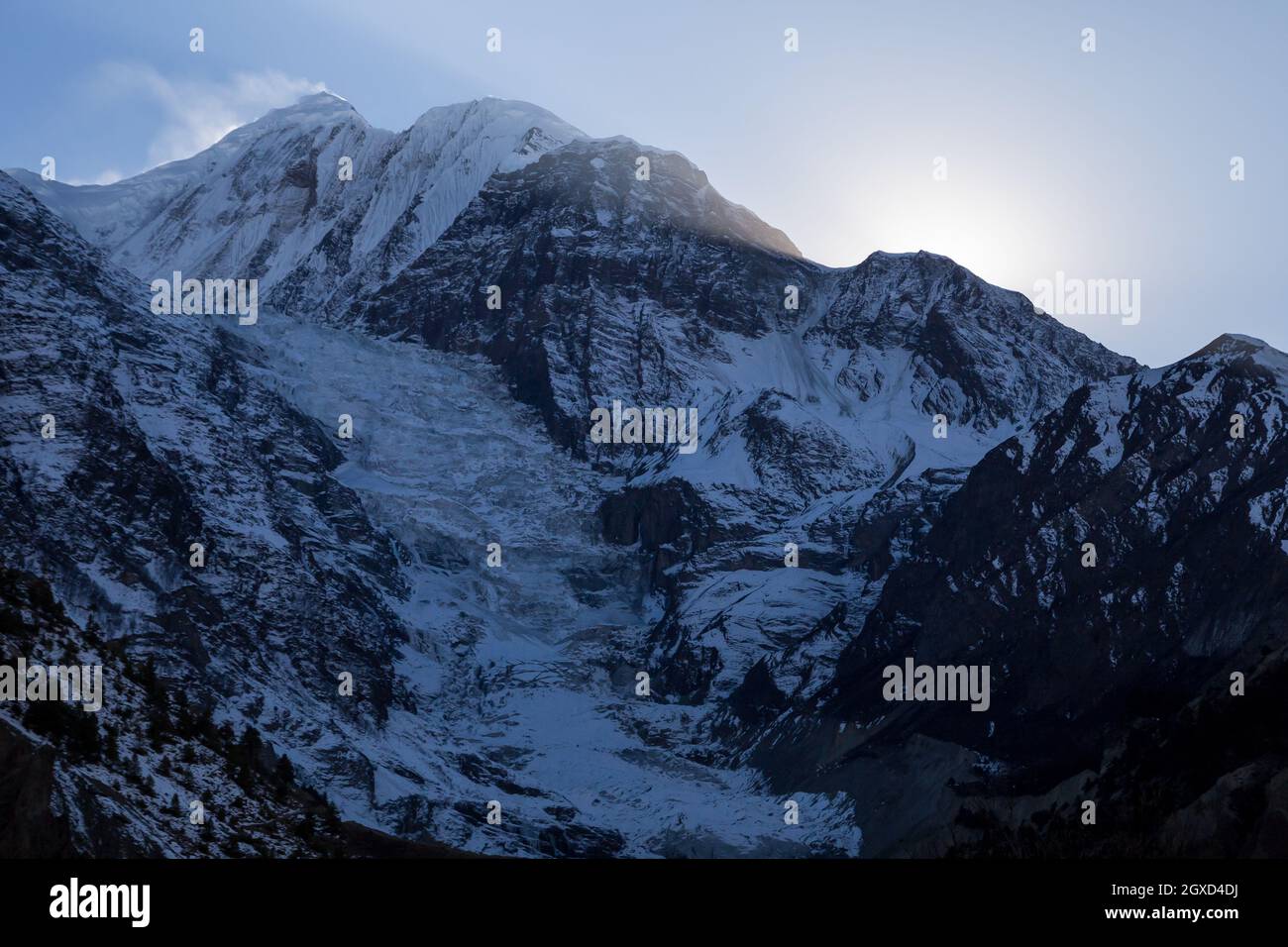 Hohe steile Hänge von schneebedeckten Bergen liegen im Himalaya unter farbenfrohem Himmel in Nepal Stockfoto