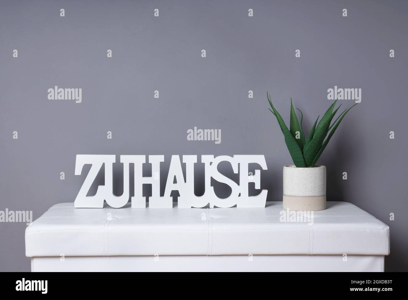 das deutsche Wort zuhause bedeutet zu Hause als moderne Inneneinrichtung neben Topfpflanzen Stockfoto