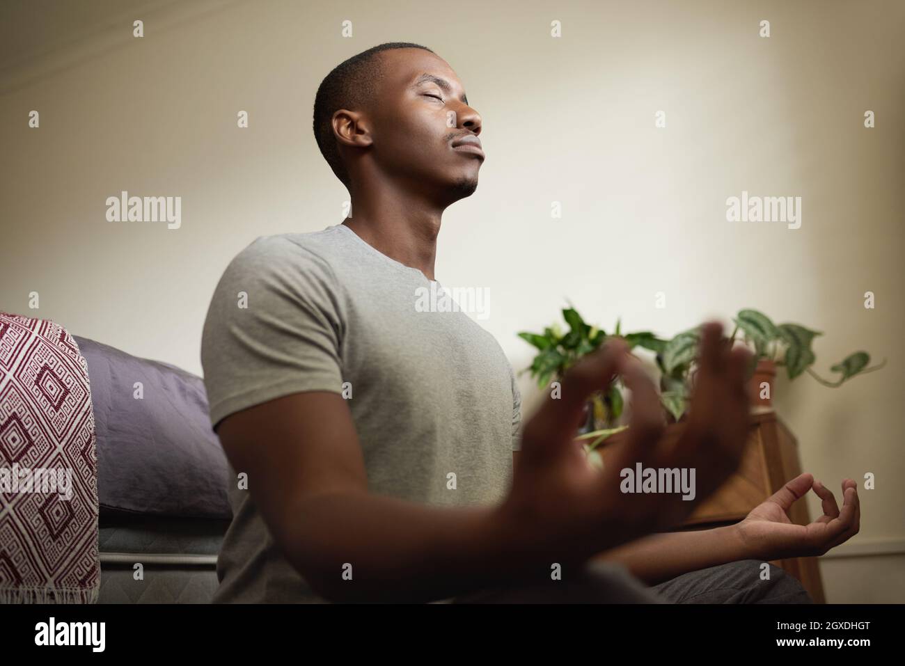 Junger afrikanischer Mann, der zu Hause in seinem Schlafzimmer meditiert Stockfoto