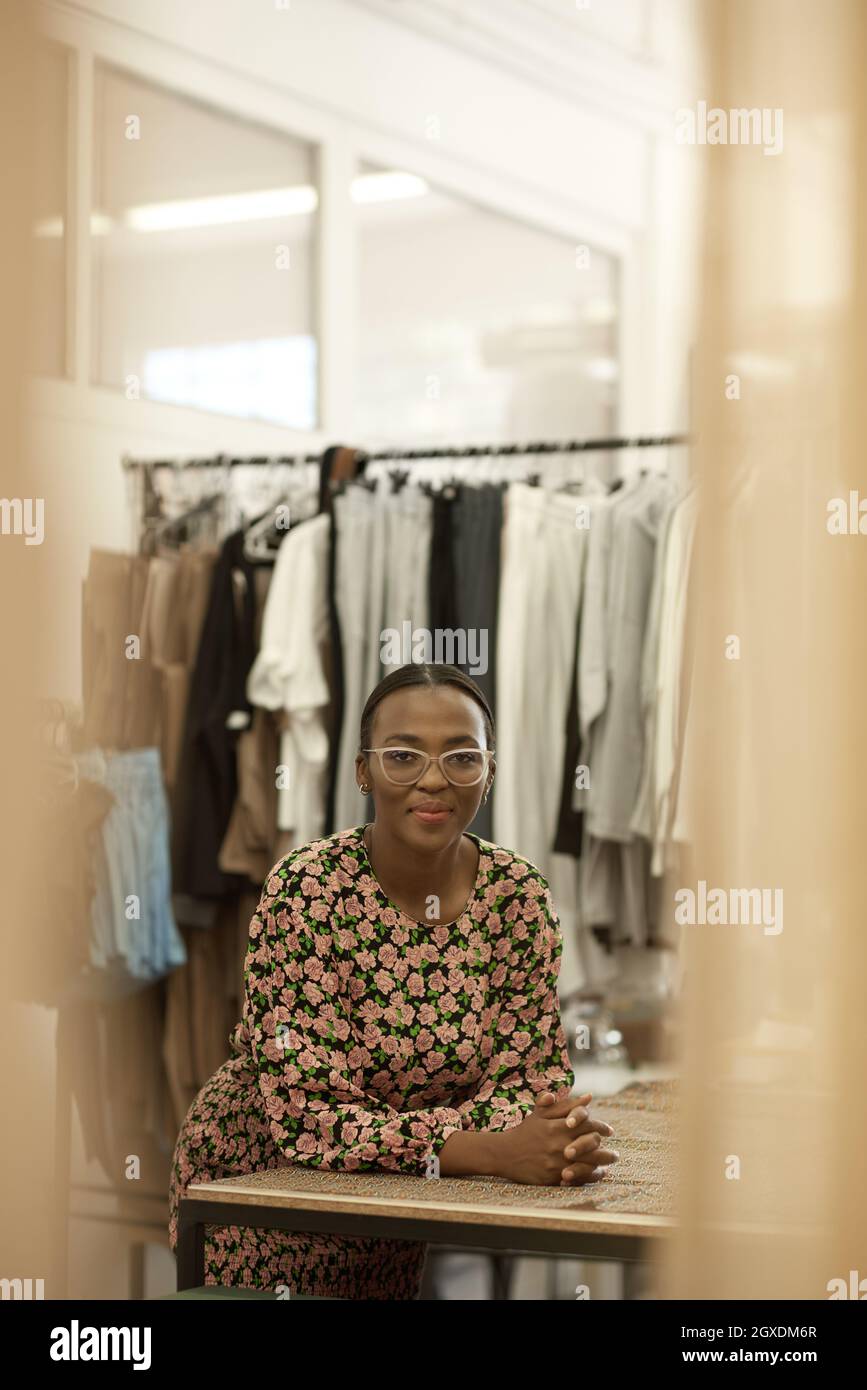 Die junge afrikanische Designerin lehnt sich in ihrem Studio auf eine Bank Stockfoto