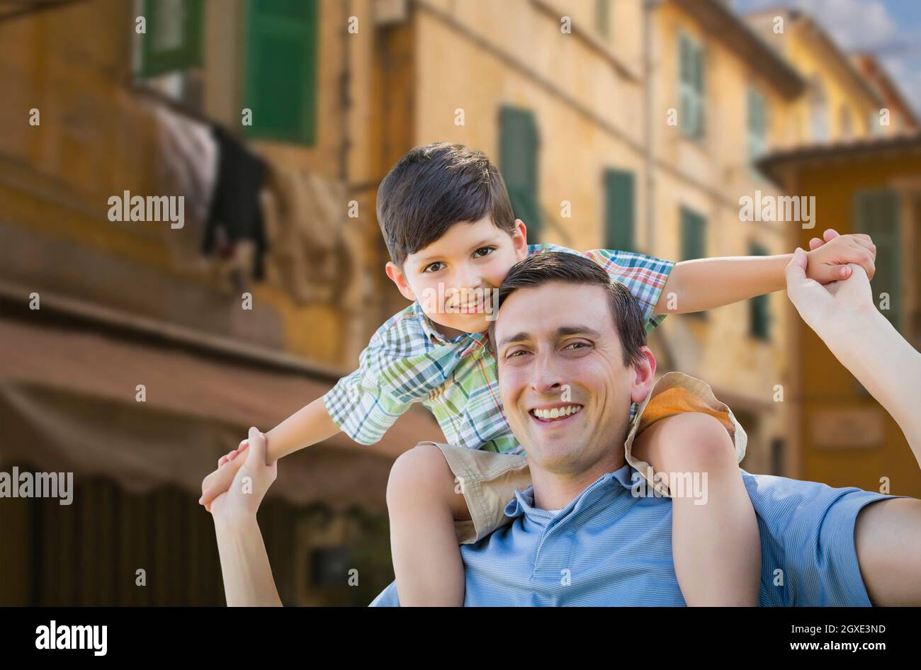Mixed Race Vater und Sohn spielen Piggyback auf den Straßen Frankreichs. Stockfoto