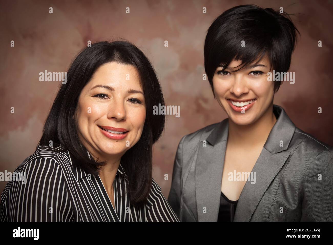 Attraktives multiethnisches Mutter-Tochter-Studio-Portrait auf Muslin-Hintergrund. Stockfoto