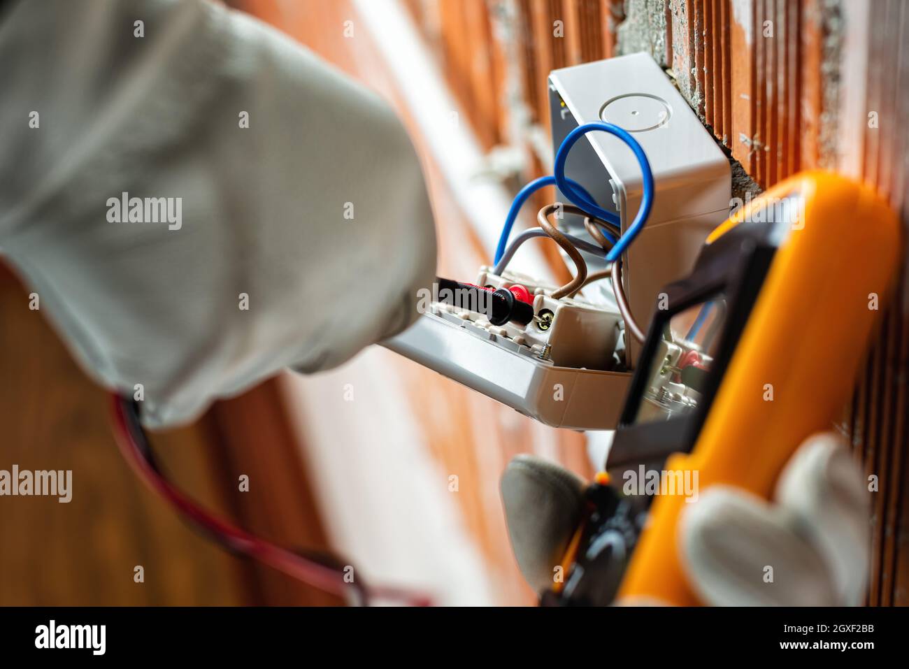 Ansicht von unten. Elektriker bei der Arbeit mit dem Tester misst die Spannung in einem elektrischen System. Sicheres Arbeiten mit Schutzhandschuhen. Konstruieren Stockfoto