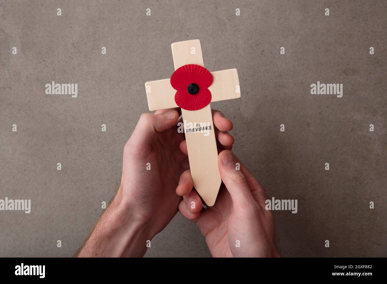 Ein roter Erinnerungsmohn auf einem Holzkreuz. Konzept des militärischen Gedenktages Stockfoto