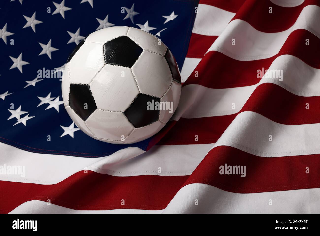 Nahaufnahme getragener schwarz-weißer Fußball-Fußball über dem Hintergrund der amerikanischen Flagge, Blick aus dem Hochwinkel Stockfoto Nahaufnahme getragener schwarz-weißer Fußball-Fußball über dem Hintergrund der amerikanischen Flagge, Blick aus dem Hochwinkel Stockfoto