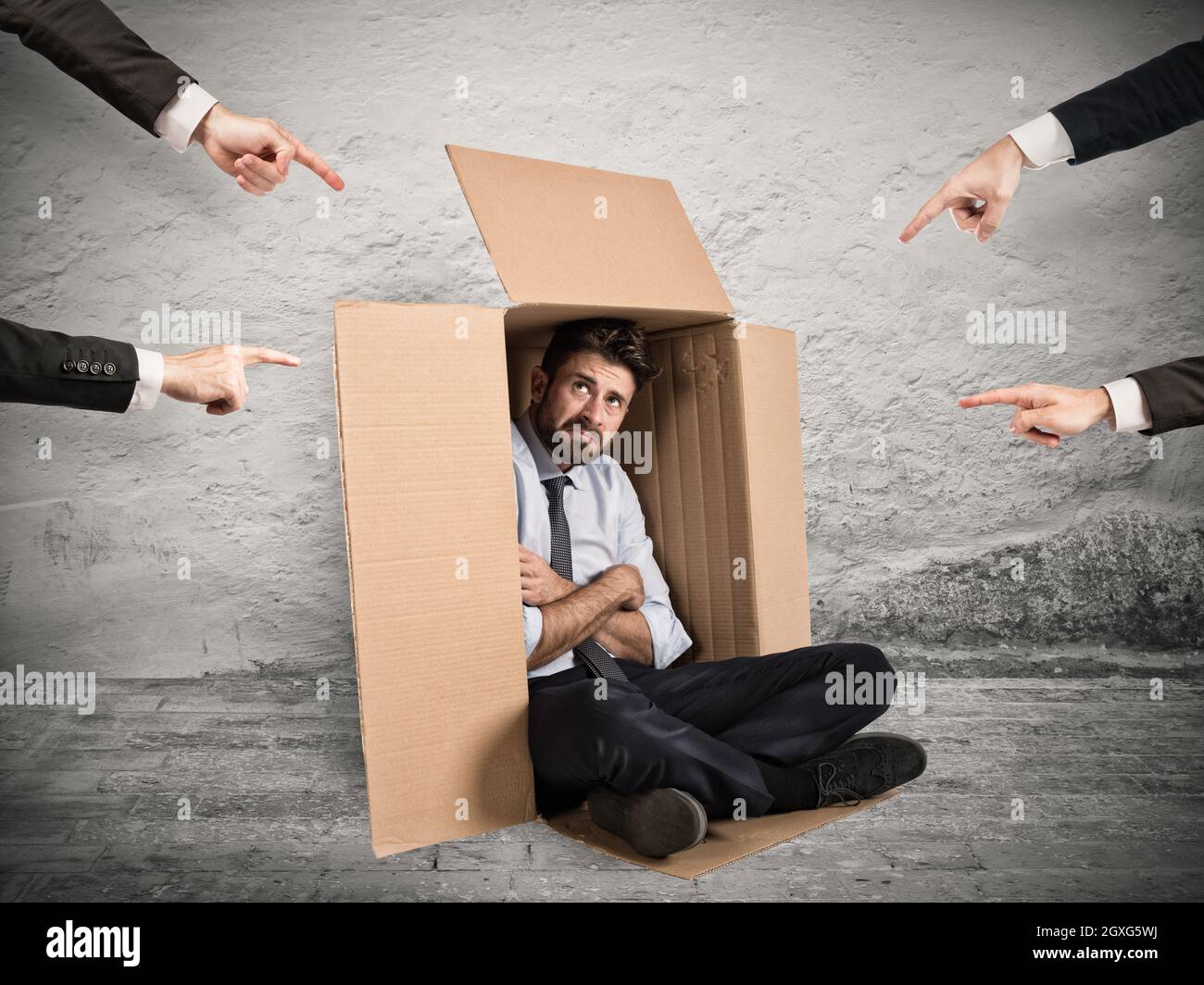 Geschäftsmann von Kollegen angezeigt, die sich in einem Karton versteckt haben Stockfoto