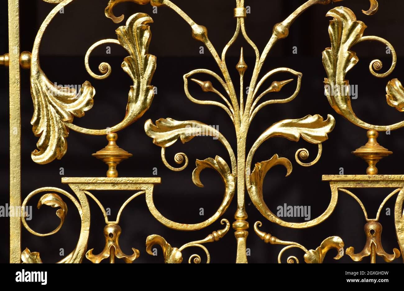 Eine Nahaufnahme von goldverzierten Metallarbeiten an Palasttoren vor schwarzem Hintergrund Stockfoto