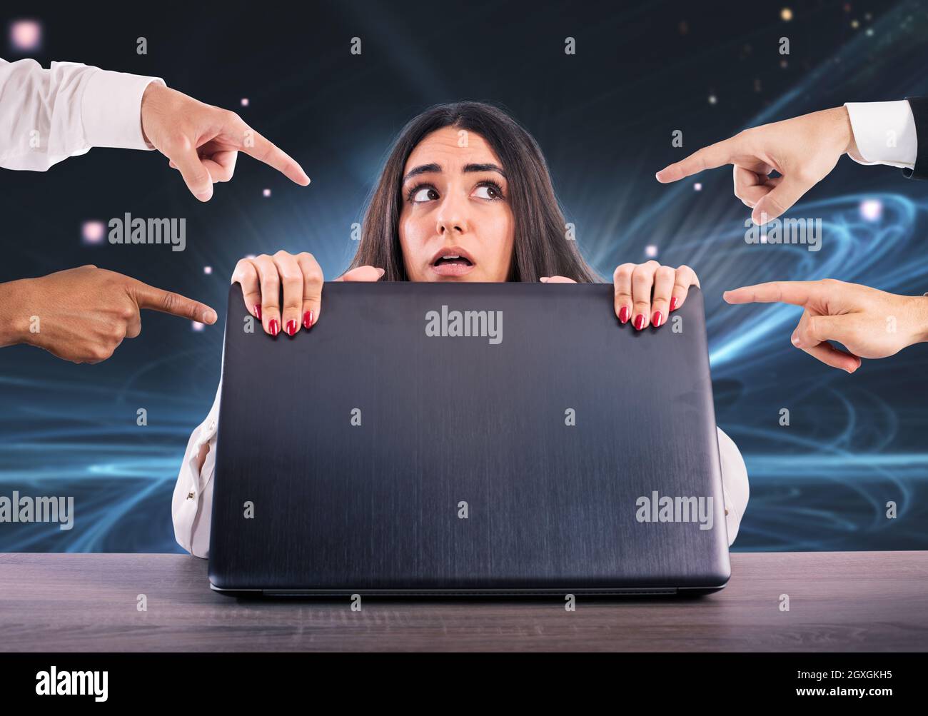 Mädchen versteckt sich hinter einem Laptop. Sie ist Opfer von Cybermobbing Stockfoto